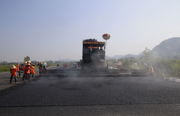 2019年8月，宜春經(jīng)開區(qū)S311路面攤鋪現(xiàn)場，工友們輔助路面兩側的分料、補窩等作業(yè)